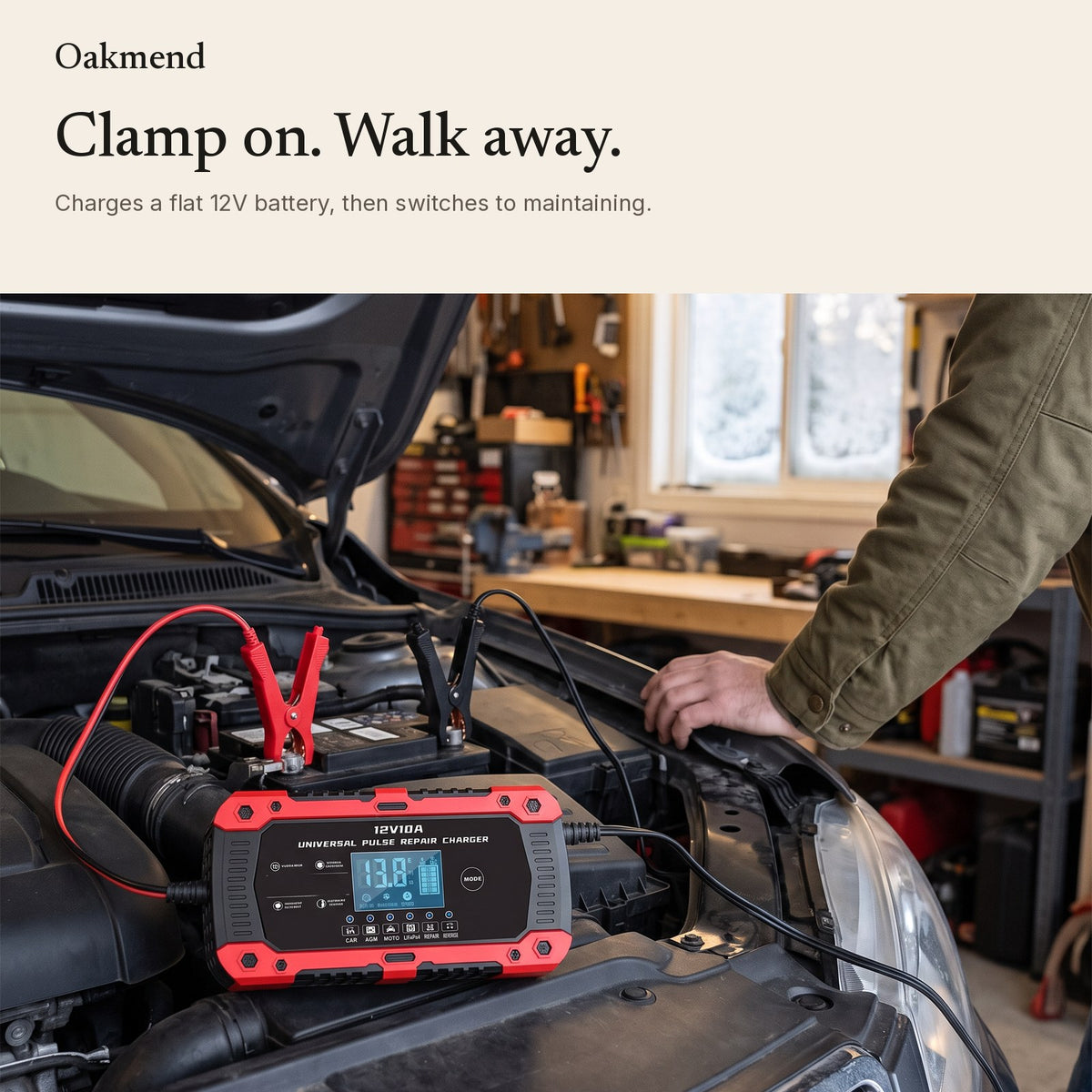 Battery charger clamped to a car battery under the hood in a garage